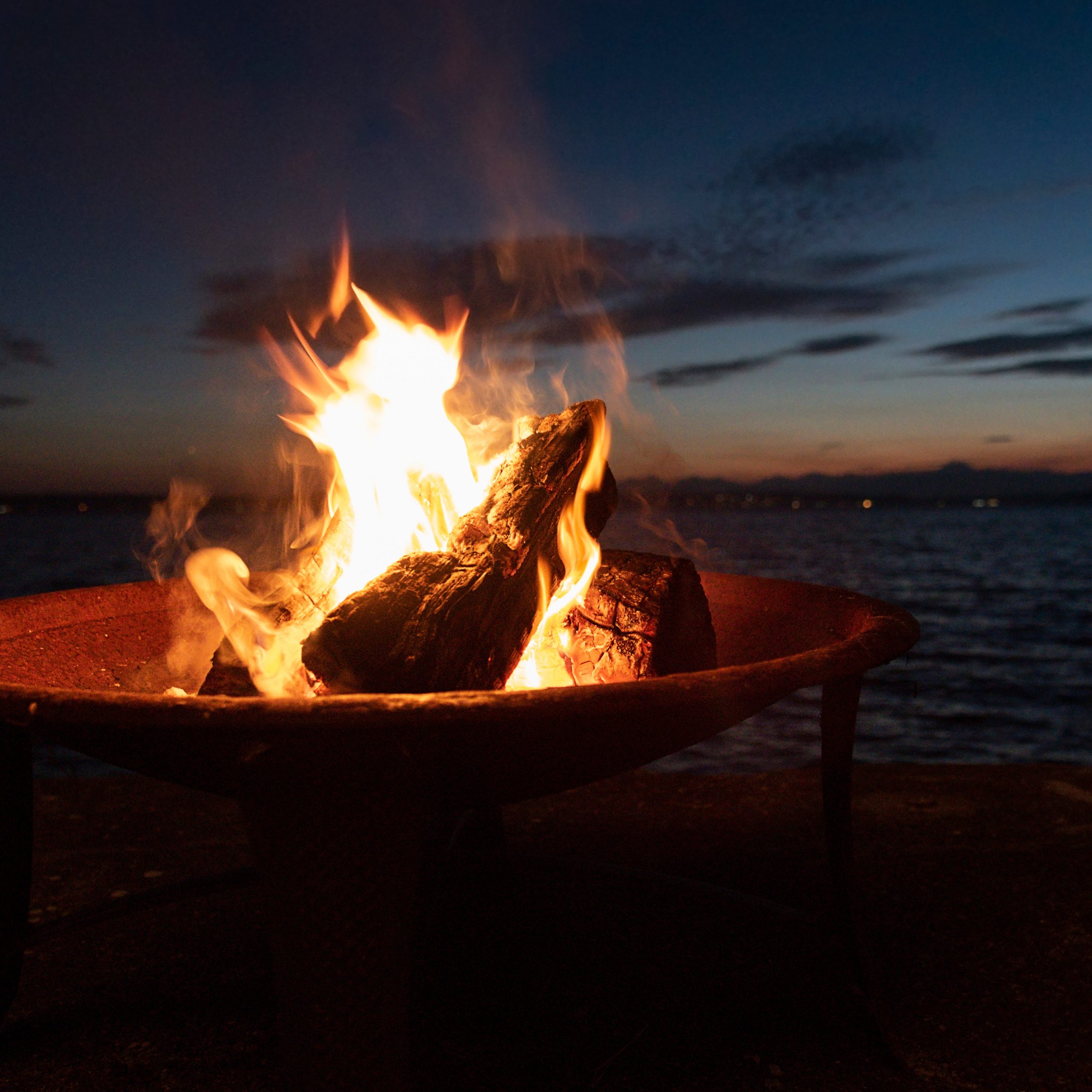 beach-fire-pit-with-sandal-wearing-feet-at-sunset-2026-03-17-20-09-24-utc